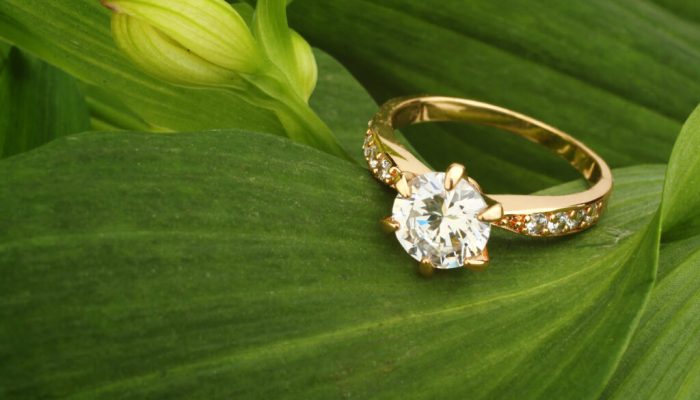 Jewellry ring with big diamond on green leafs background