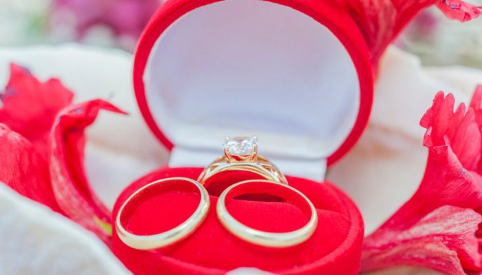 Trio of gold wedding bands and diamond ring in red velvet jewelry box