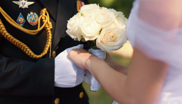 Wedding hands. Hands of the officer in white gloves and hands of his bride with a wedding bouquet from white roses during the wedding ceremony in the fresh air